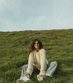 a woman sitting in the grass on top of a hill