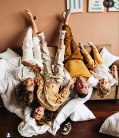 three people laying on a bed with their feet up in the air and one person lying down