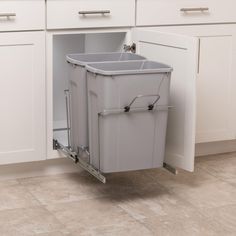 a trash can sitting in the middle of a kitchen floor next to white cupboards