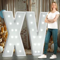 a woman standing in front of a large letter with lights on it's sides