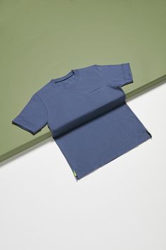 a blue t - shirt sitting on top of a white table next to a green wall