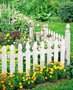 a white picket fence surrounded by flowers and greenery