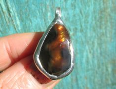 This lovely little handmade pendant features a natural Fire Agate stone, from the Deer Creek Mine in Arizona, USA. The Fire Agate is an tear drop  shape, with a nice polish. The gem looks brown in the shade but in the sunlight it displays rainbow iridescence. There is also a Botryoidal (bubbly looking) structure inside the stone that is just fascinating. The Fire Agate is bezel set with lead free silver bearing solder, and has a Sterling Silver bail (loop on top). Would look cool on a cord/chain Brown Teardrop Agate Jewelry, Deer Creek, Arizona Usa, Fire Agate, Agate Pendant, Handmade Pendant, Agate Stone, Tear Drop, Handmade Pendants