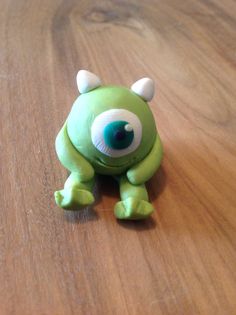 a green toy with big eyes sitting on top of a wooden table