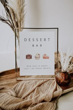 a desert bar sign sitting on top of a wooden tray next to some dried plants