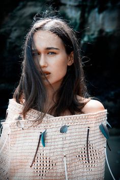 a woman with long dark hair and blue eyes is posing for the camera, wearing an off - white sweater