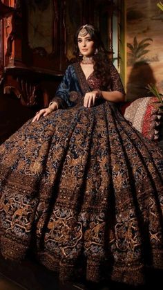 a woman sitting in a chair wearing a dress with an intricate pattern on it's skirt