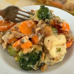 a white plate topped with broccoli, cauliflower and carrots next to a fork