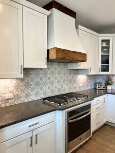 a stove top oven sitting inside of a kitchen next to white cupboards and drawers