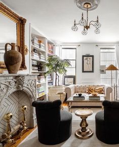 a living room filled with furniture and a fire place under a chandelier in front of a fireplace