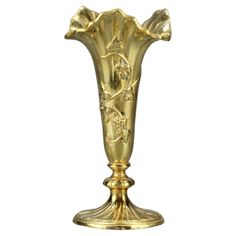 a gold vase is sitting on a white surface and it has flowers in the center