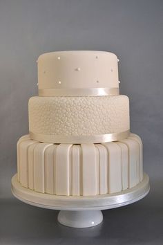 three tiered cake sitting on top of a white pedestal