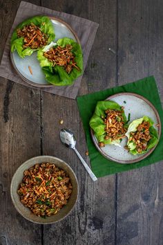 lettuce wraps with meat and vegetables in them on top of a wooden table