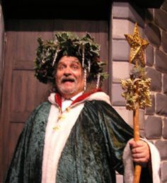 a man dressed in costume holding a stick and wearing a wreath on top of his head