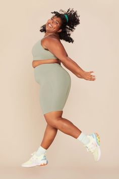 a woman in a green dress is smiling and posing with her arms spread out to the side