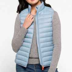 This Puffer Vest Is A Spring Wardrobe Staple. Made From Lightweight Nylon With Animal-Free Plumtech Padding, This Iconic Style Features A Standing Collar, Secure Zipped Pockets And Lycra Trims At The Cuffs And Hem. The Signature Orange Zip Pullers Add A Distinctive Touch. Light Blue Puffer Vest Outfit, Versatile Nylon Outerwear For Work, Versatile Solid Outerwear For Travel, Lightweight Casual Outerwear In Solid Color, Spring Nylon Outerwear, Spring Solid Nylon Outerwear, Spring Travel Outerwear With Zipper Closure, Versatile Outerwear For Spring Outdoor Activities, Versatile Spring Outerwear For Outdoor Activities