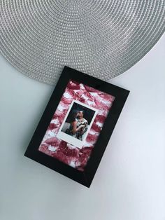 a red and white tie - dyed photo frame hanging on the wall next to a silver circle