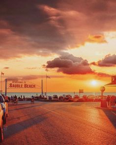 cars are parked on the side of the road as the sun sets in the background