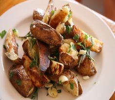 a white plate topped with potatoes covered in herbs