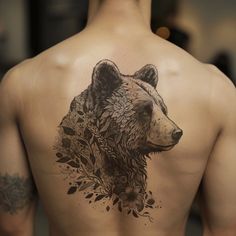 a man's back with a bear tattoo on his left side and flowers all over it