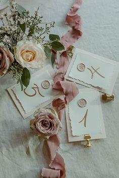 some flowers and cards on a table with ribbons around the place settings for each card