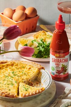 a table topped with pies and salad next to bottles of sauce on top of plates