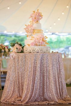 a wedding cake on top of a table with pink flowers and greenery around it