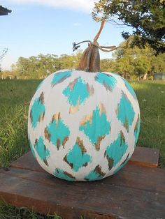 a painted pumpkin sitting on top of a wooden block