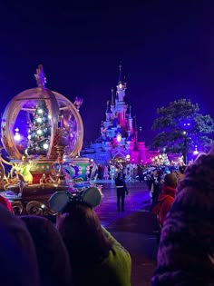 people are standing in front of a float with lights on it at the disneyland world christmas parade