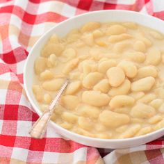 a white bowl filled with food on top of a red and white checkered table cloth