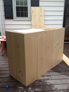 a wooden box sitting on top of a deck next to a building and a window