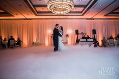 a bride and groom standing in the middle of a cloud filled dance floor