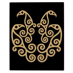 a black and gold plate with an intricate bird design on the front, along with swirls in the back