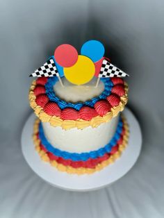 a birthday cake decorated with colorful icing and balloons