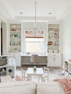 a living room filled with furniture and a chandelier hanging from the ceiling over a window