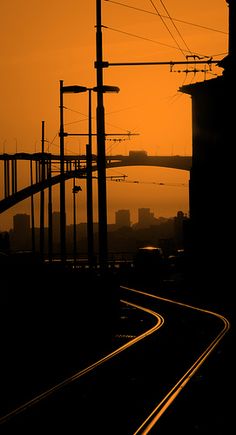 the sun is setting over an urban area with train tracks and power lines running through it