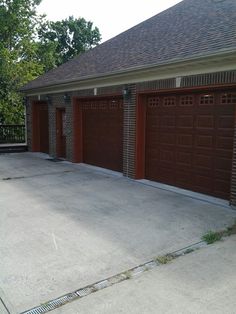 two brown garage doors on the side of a brick building