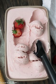 an ice cream dish with strawberries in it and two scoops on the side