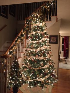 a christmas tree is decorated with lights and garlands on the bannister stairs