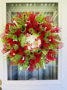 a red and green christmas wreath hanging on the front door