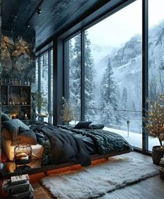 a bedroom with a large window overlooking the mountains and snow covered trees is shown in this image