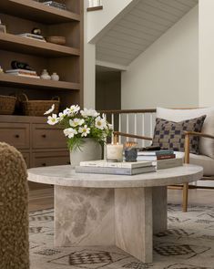 a table with flowers and books on it in front of a book shelf filled with books