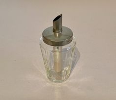 a glass jar with a metal lid and a spoon sticking out of the top, sitting on a white surface