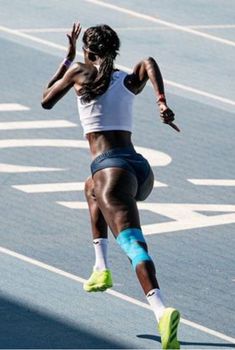 a woman running on a track with her hands in the air and one leg up