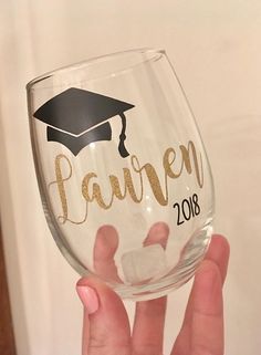 a person holding up a wine glass with the word lauren on it and a graduation cap