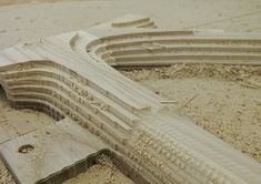 a close up of a wooden structure on the ground with sand around it and another object in the background