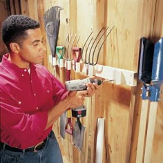 a man is holding a drill in his hand while working on a wall mounted tool rack