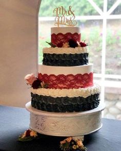 a three tiered wedding cake with red, white and black layers