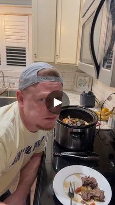 a man with a blindfolded head is looking at a plate of food on the kitchen counter