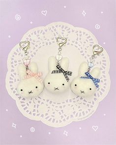 three white stuffed animals are on a doily with hearts and bows in the shape of bunnies